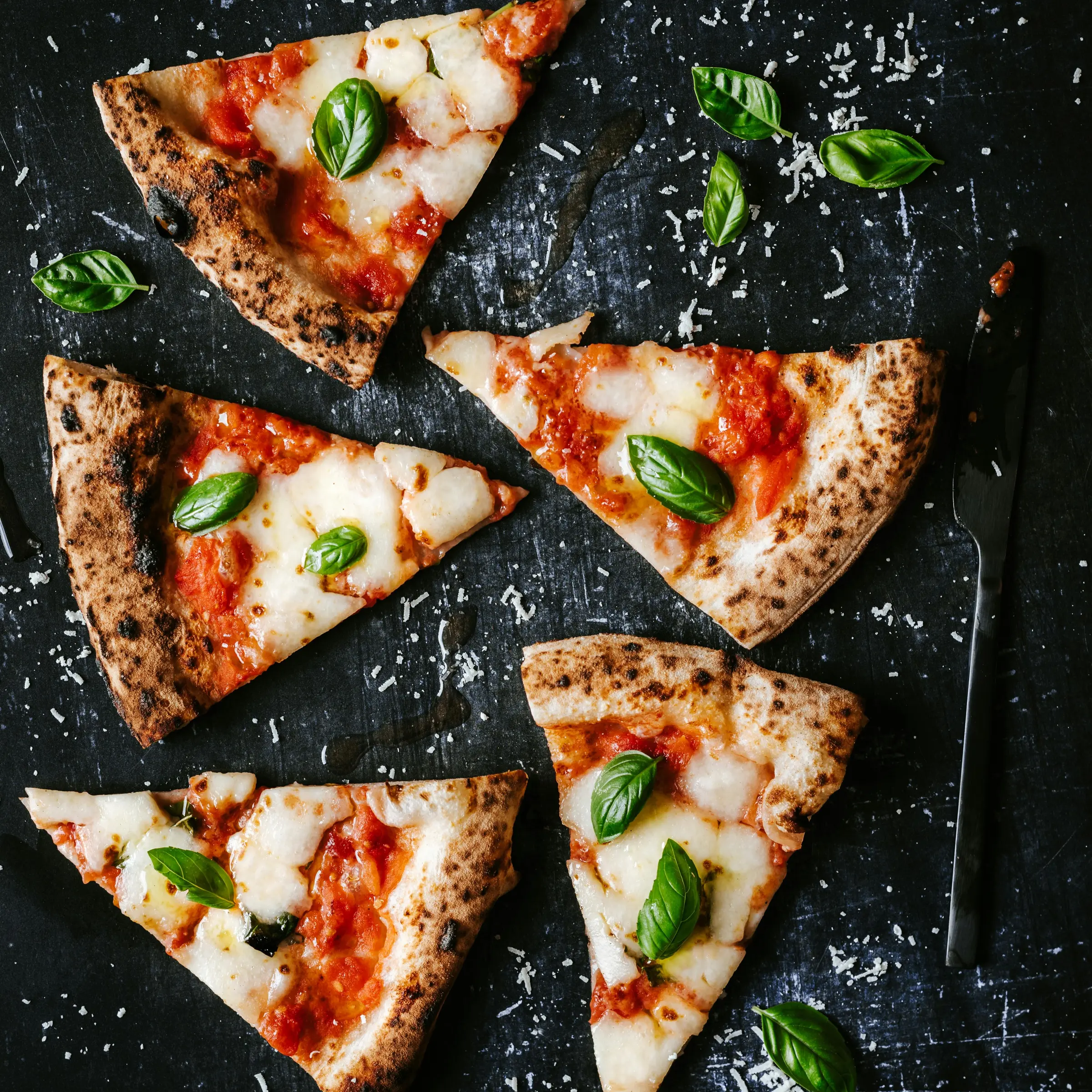 This image is five slices of already cut up pizza slices rotated in multiple directions, the toppings are plain cheese and basil leaves.